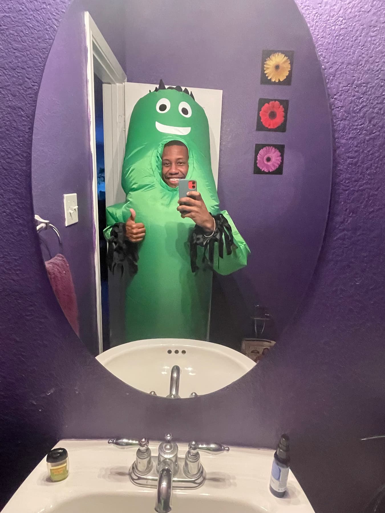 A bathroom-mirror photo in Texas, in a green inflatable costume