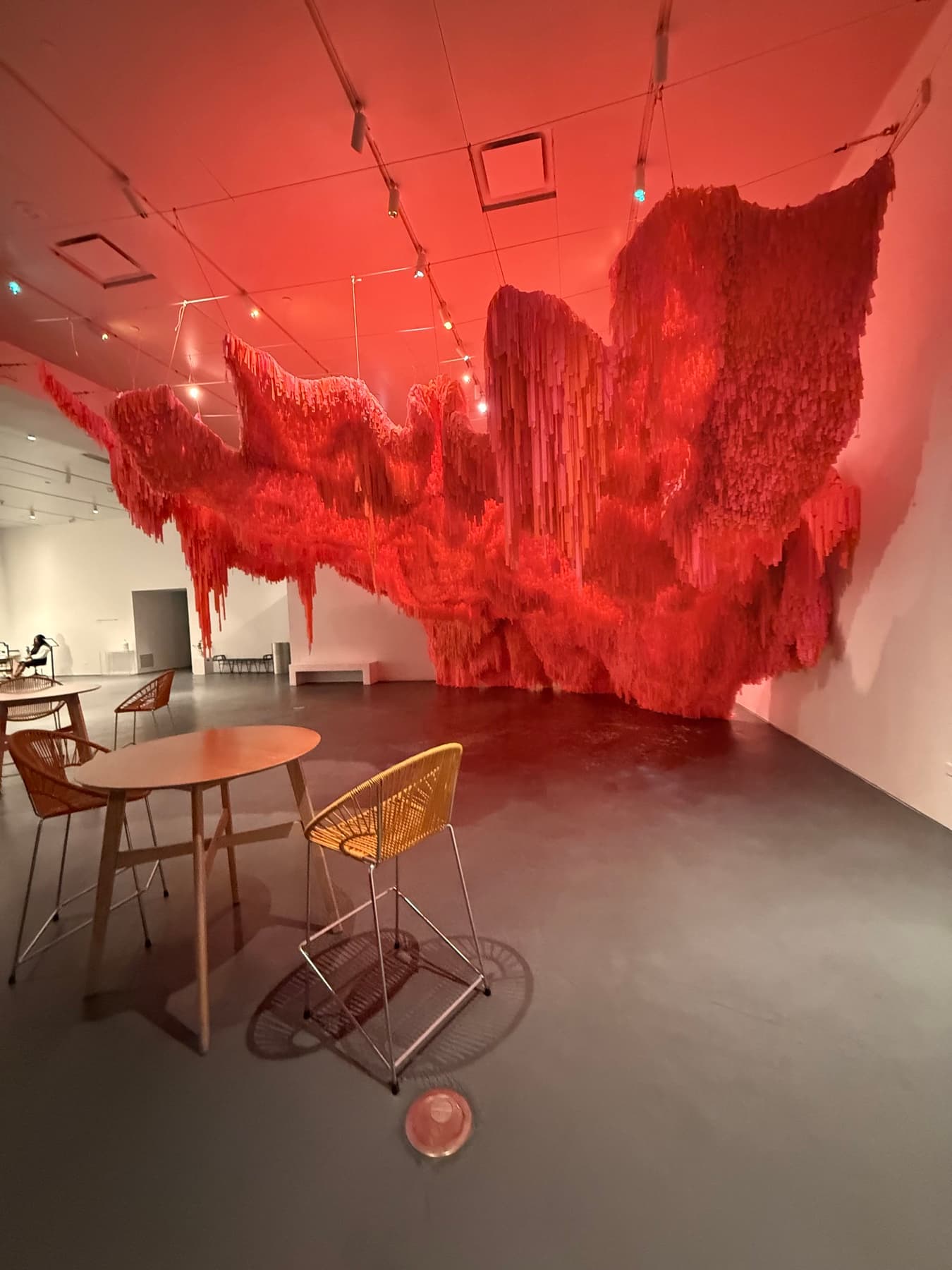 A red hanging sculpture in a quiet museum gallery