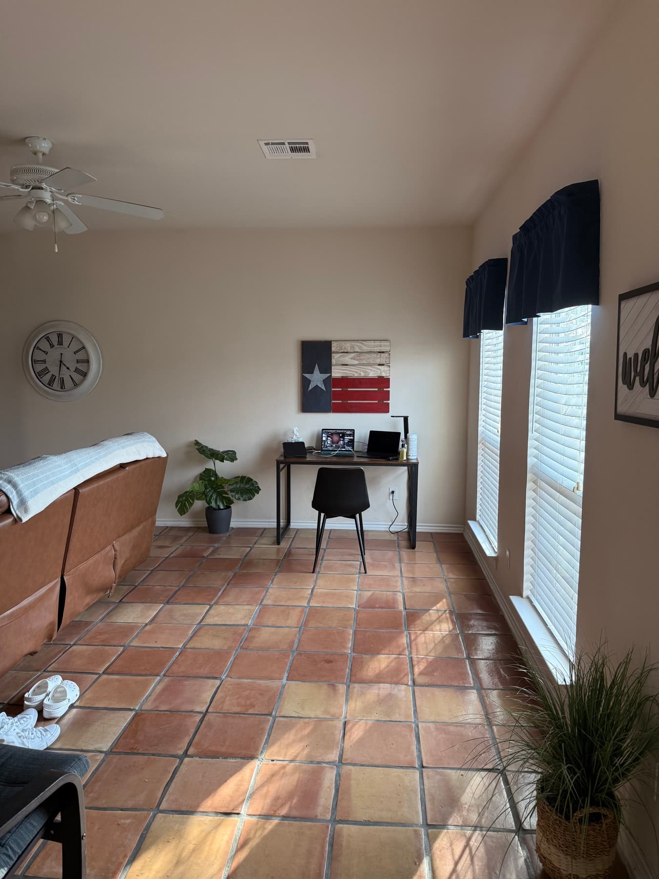 A Texas apartment desk, two closed laptops, a Texas flag on the wall